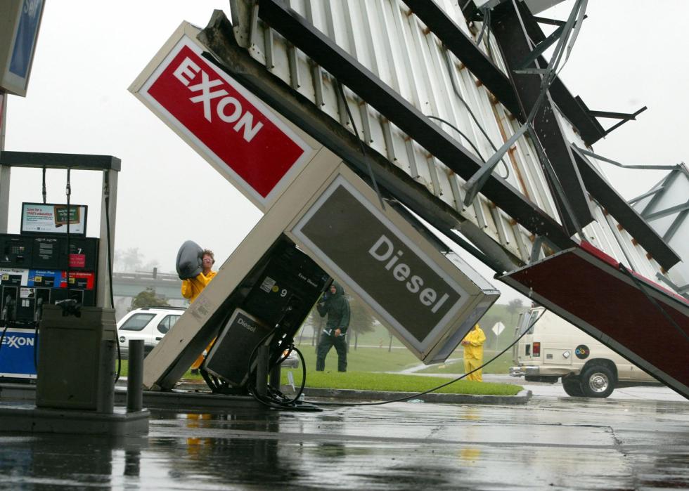 People outside a Exxon gas station that has been badly hit by a storm.