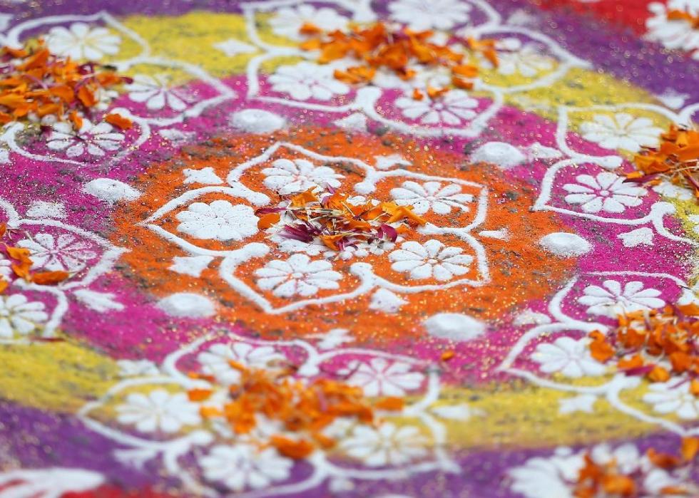 A close up of a pink, purple, and white rangoli with a floral design.
