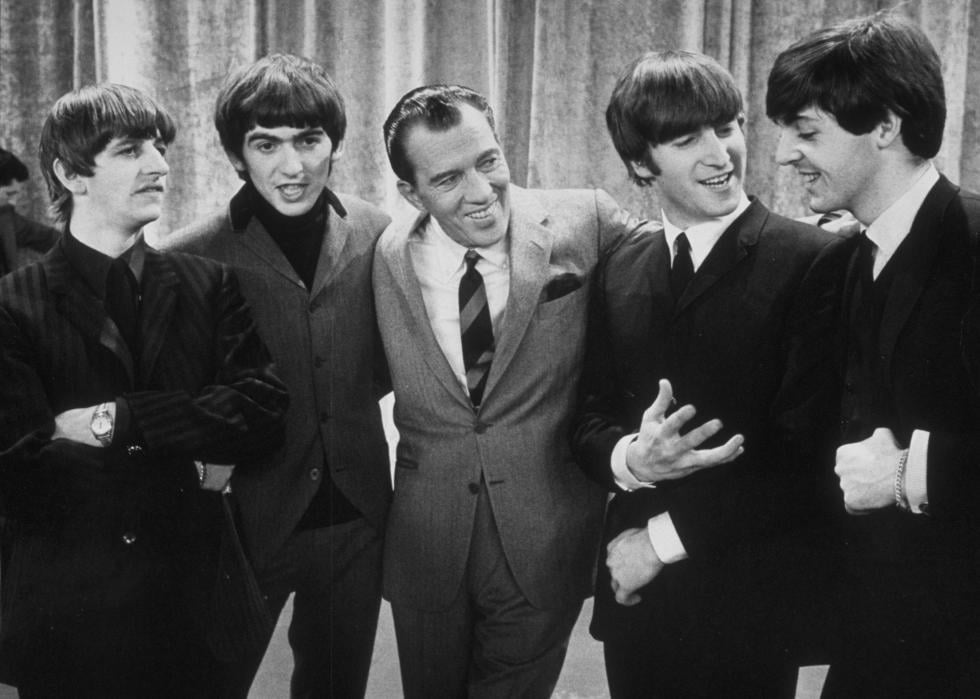 Ed Sullivan standing with the Beatles on the set of his television series