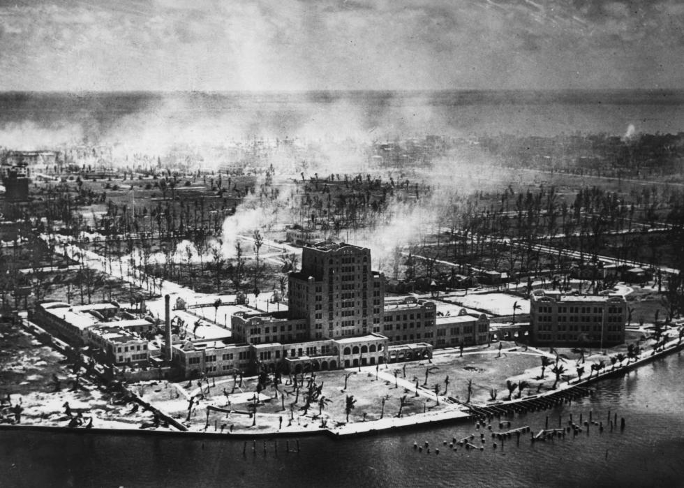 An aerial view of smoke plumes emerging from a city near the coast.