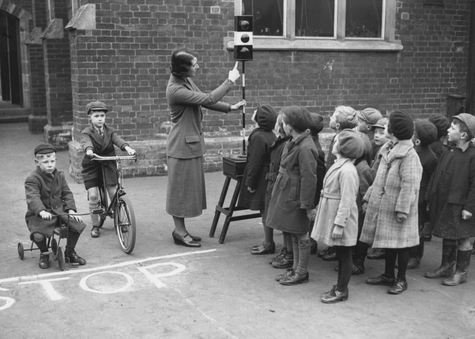 A teacher shows young children at a school how to cross the road.