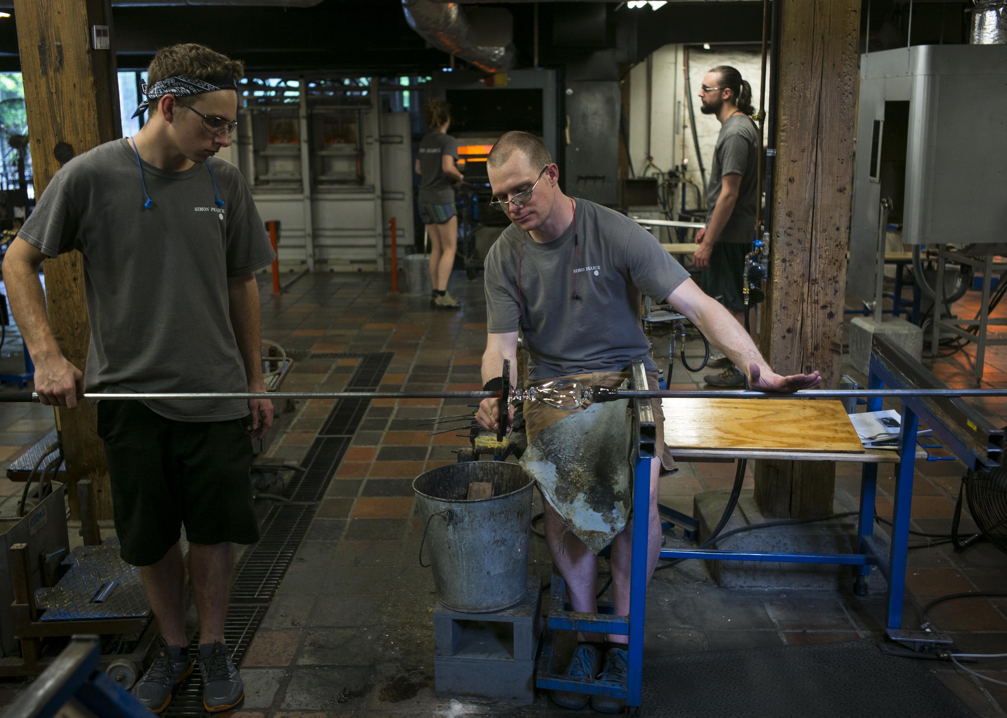 Employees at the Simon Pearce glass company work on a handmade goblet
