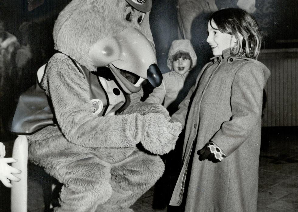 A young girl with a person dressed as Chuck E. Cheese in 1987.