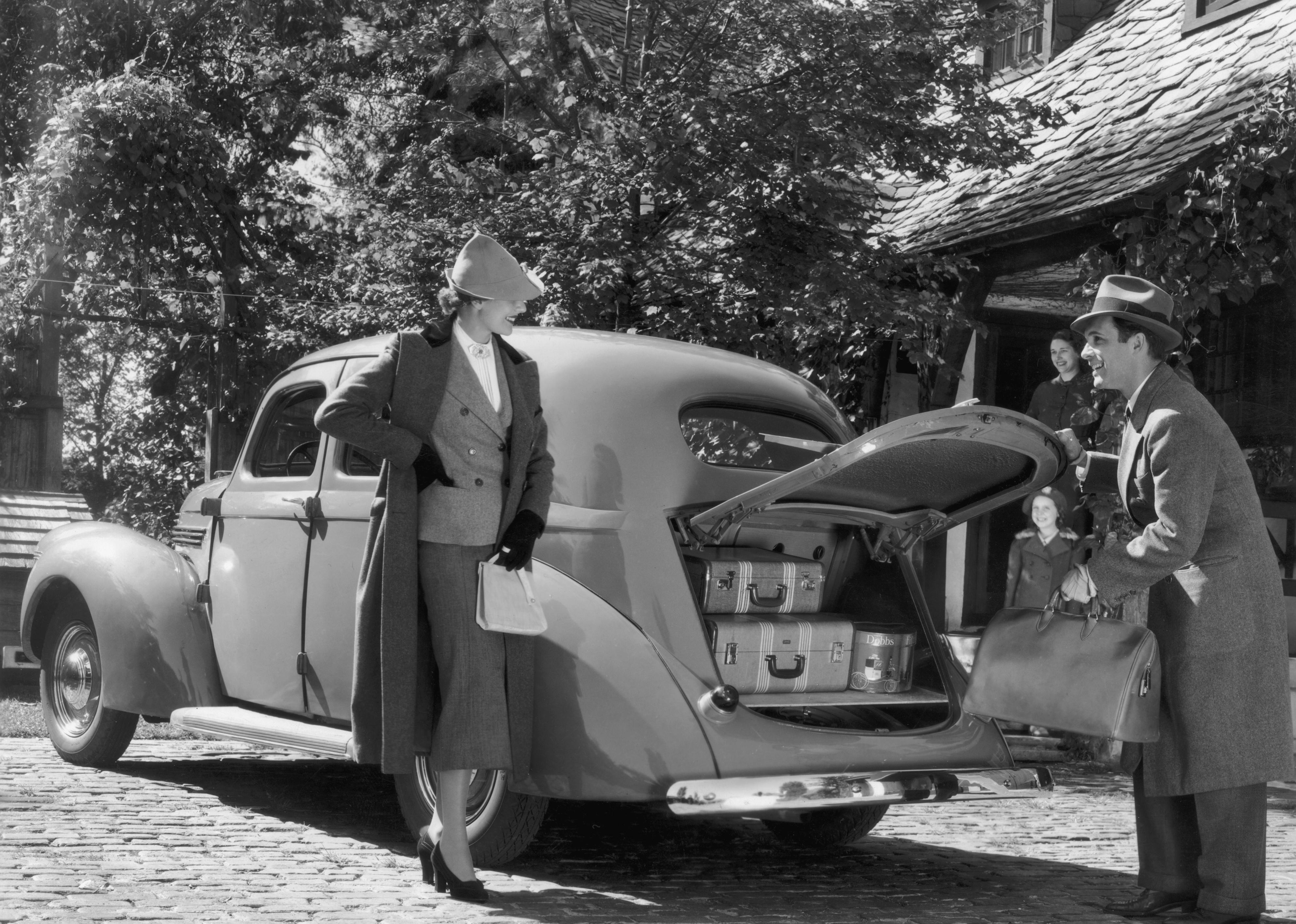 A couple prepares for a trip in their 1937 Willys sedan.