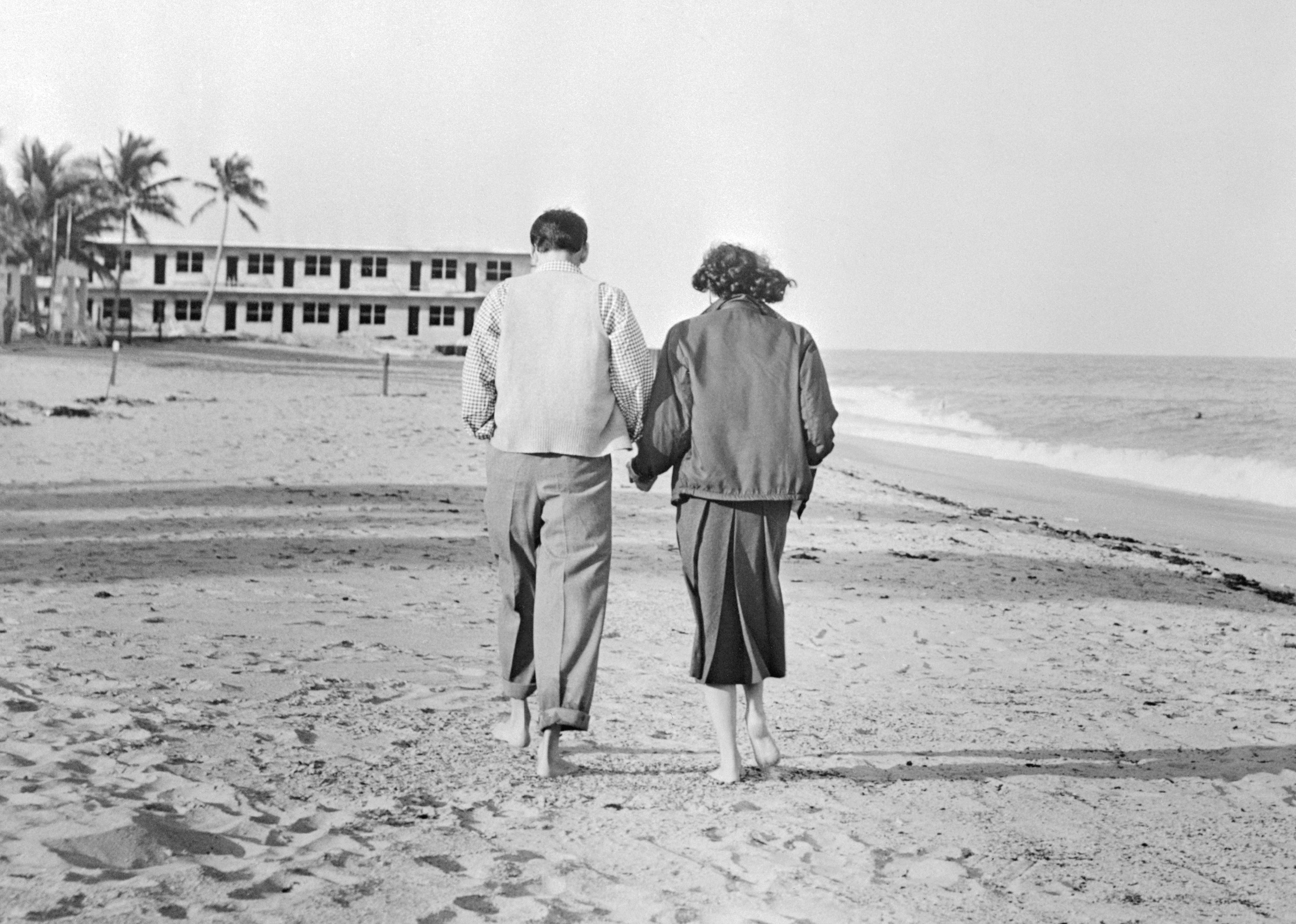 Newlyweds Frank Sinatra and Ava Gardner stroll along a beach in Miami.