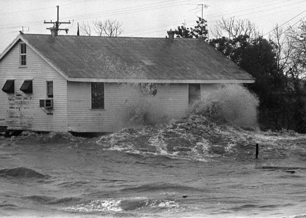 Waves from flood waters hit against a home. 