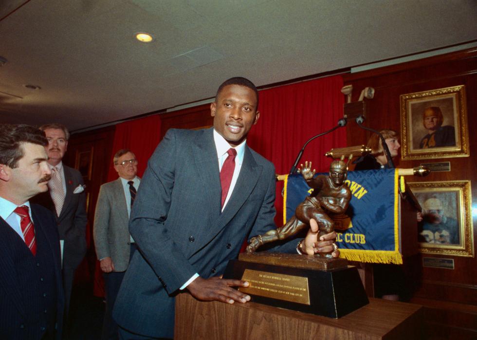 Tim Brown posing by his Heisman Trophy.