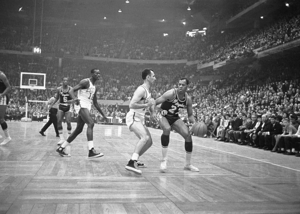 Elgin Baylor tries to maneuver the ball around Bob Cousy of the Boston Celtics