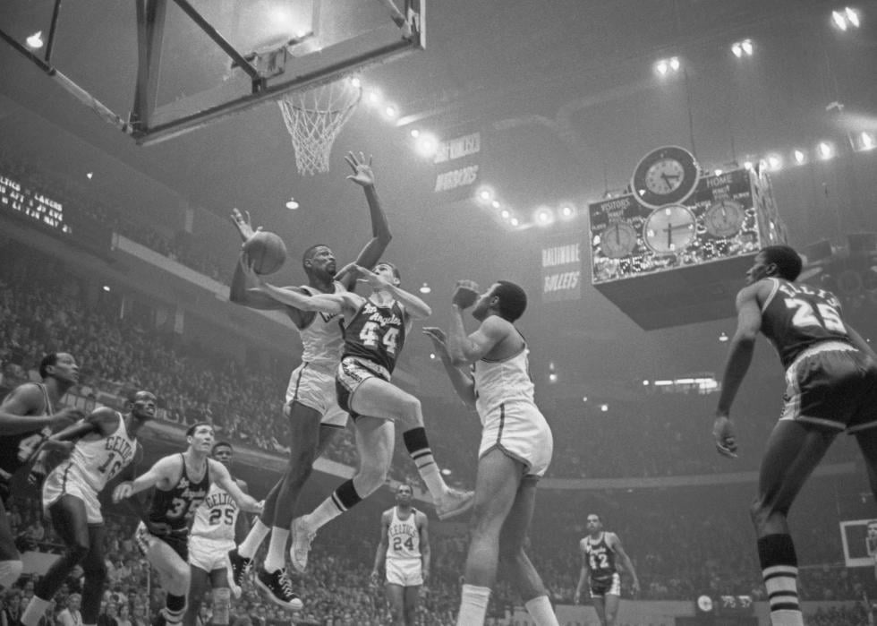 Jerry West is guarded closely as he goes in for a layup