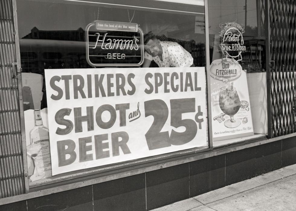 Man places sign offering "strikers special" in window of tavern