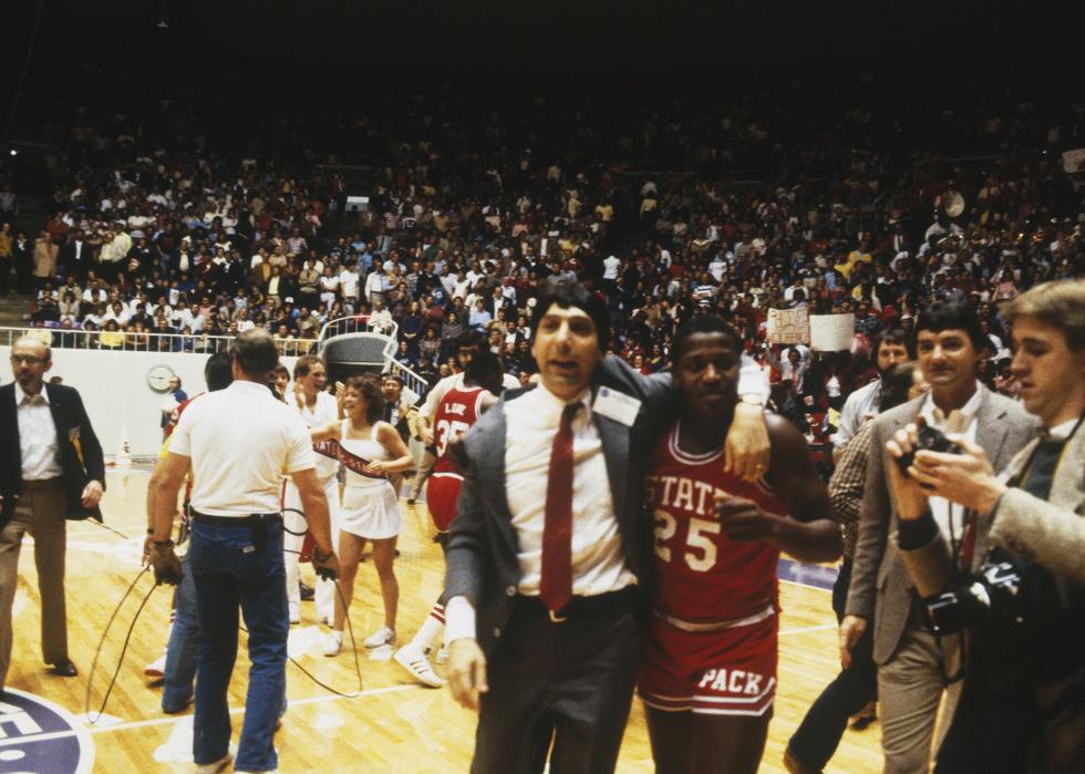 Head coach Jim Valvano of the North Carolina State Wolfpack walks off the court with a player after winning.