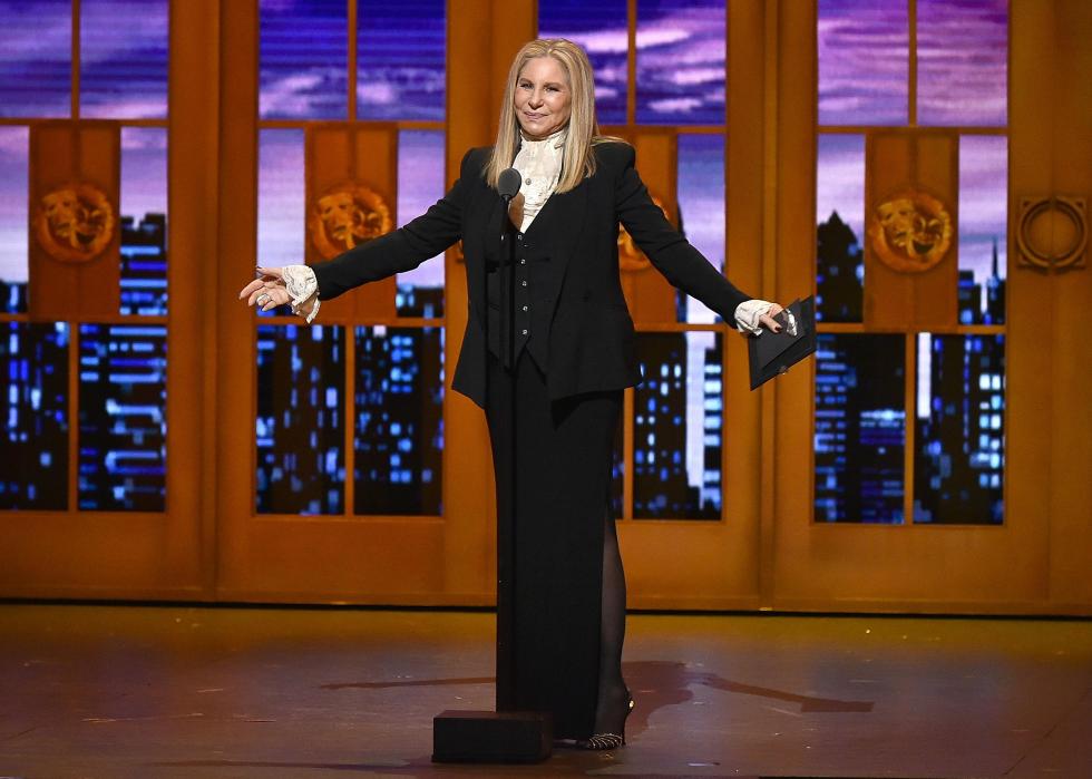 Barbra Streisand on stage standing behind a mic. 