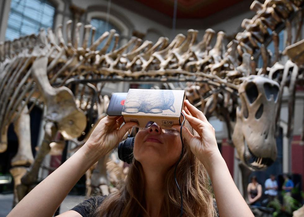 A woman uses a smartphone with a "Google Cardboard" mount for VR 