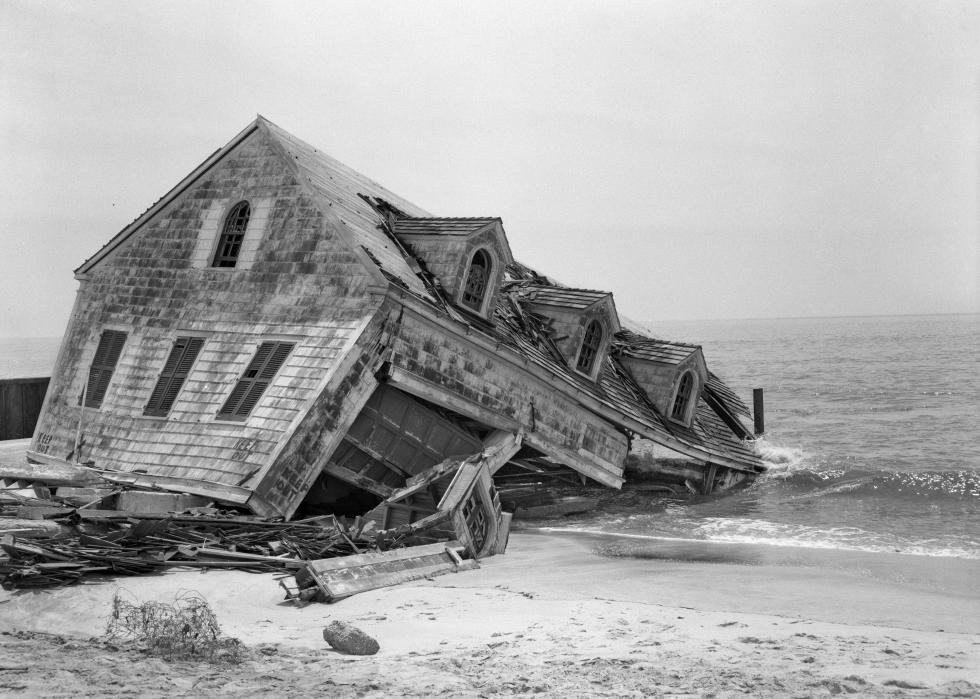 On a beach, a home collapsing into the sea.