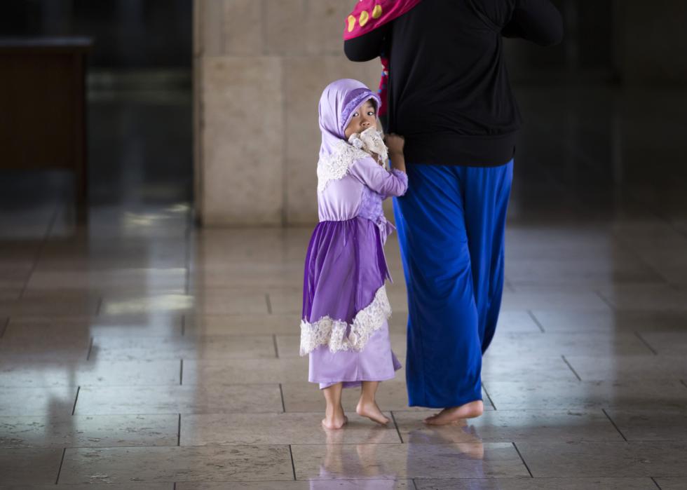 A girl walks with her mother at a mosque in Jakarta, Indon