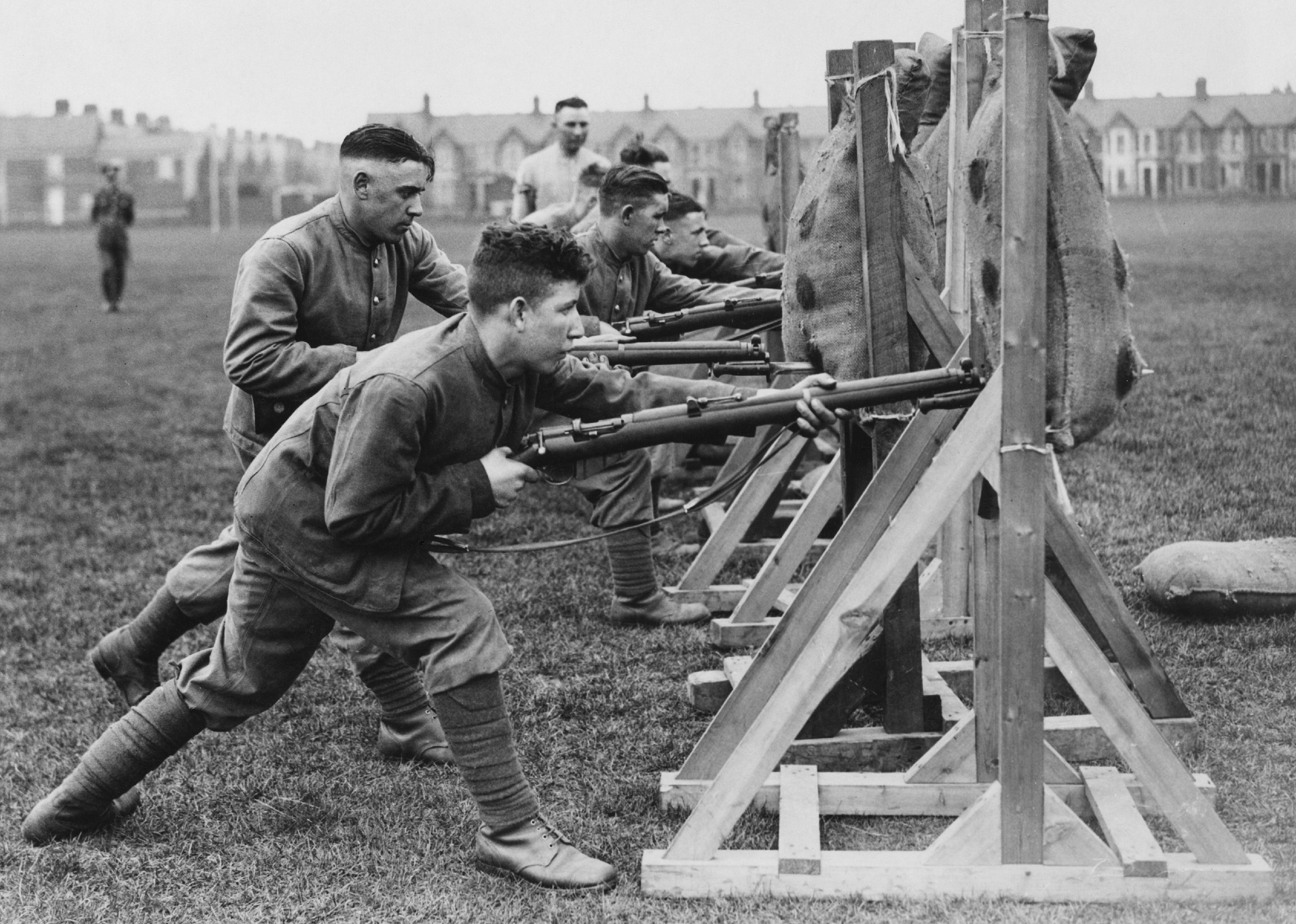 Soldiers undertake bayonet thrust practice against straw filled dummies using a bolt action rifle.