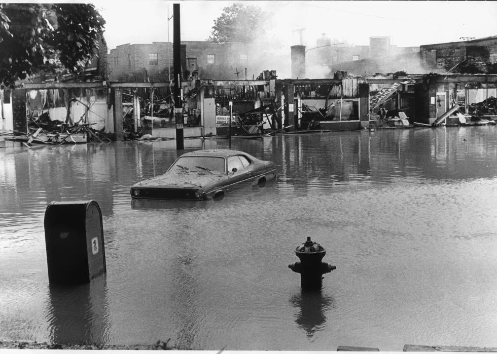 A flooded street with a car partially submerged.