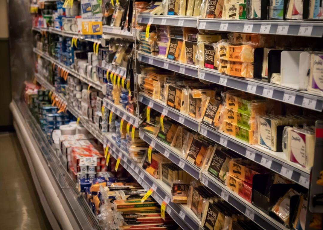 Grocery shelves stocked with various cheeses.