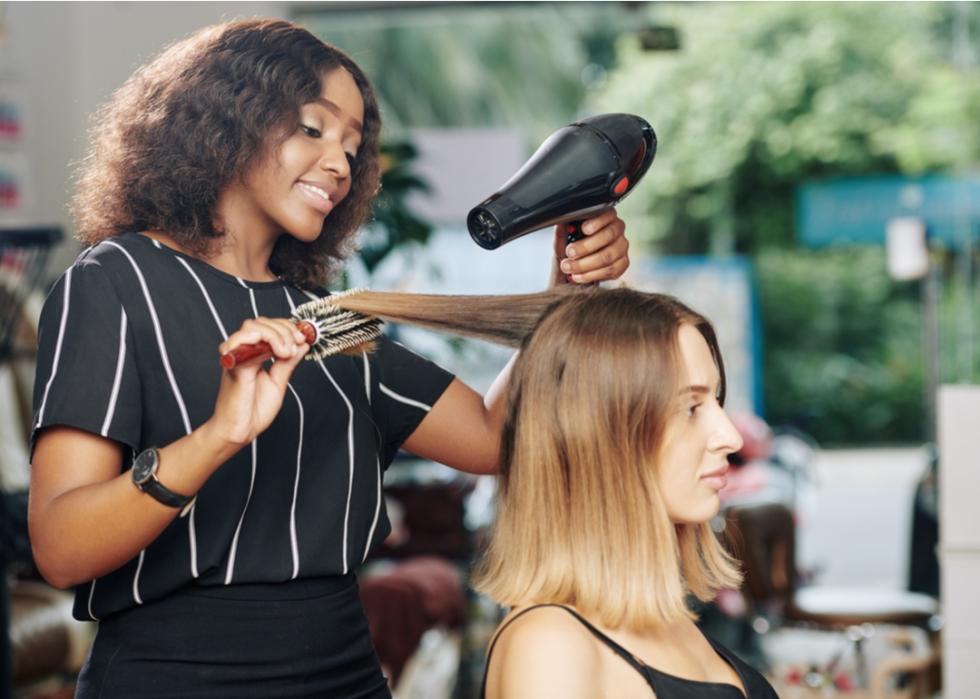 Female stylist blowdrying a client's hair.