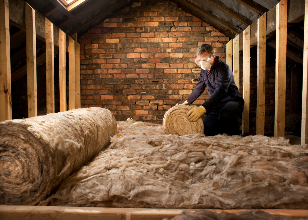 A person unrollig insulation in an attic.