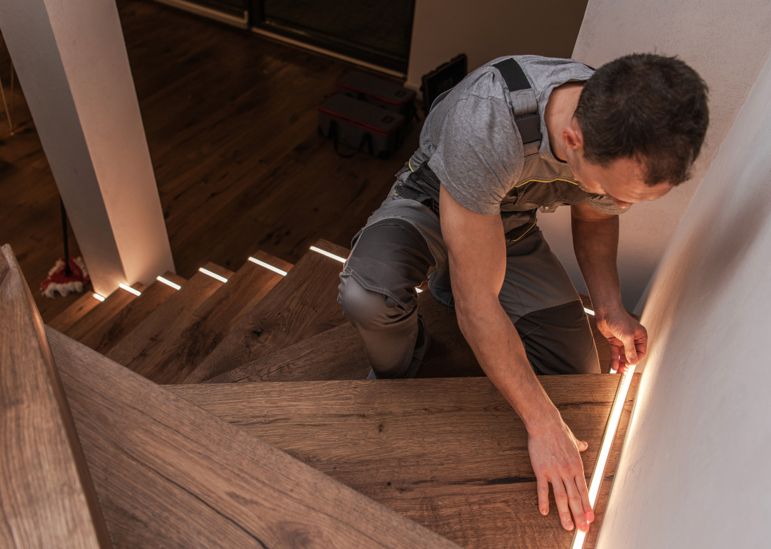 A person installing LED ligthing on his stairs.