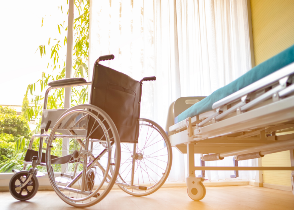 Wheelchair and hospital bed in sunny room.