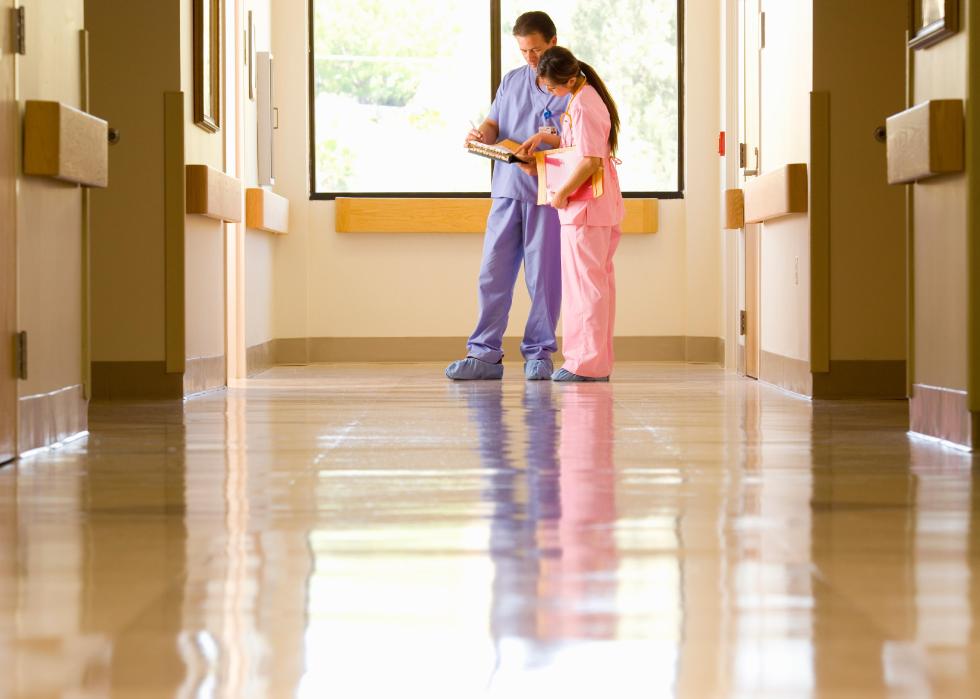 Doctor and nurse looking at a chart in the hallway.