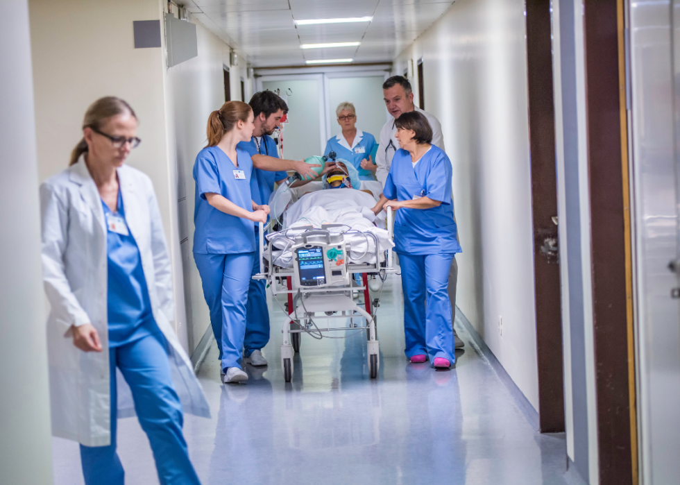 Hospital staff pushing a patient in a stretcher down a hallway.