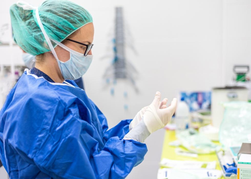 Female nurse puts on protective gloves.