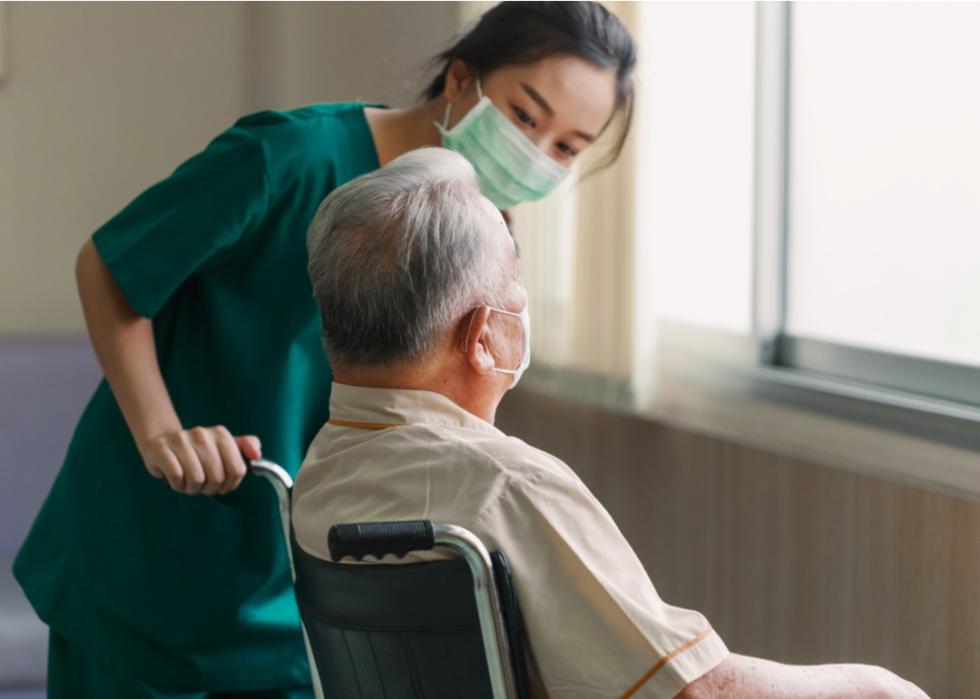 Nurse checks on elderly patient in a wheelchair.