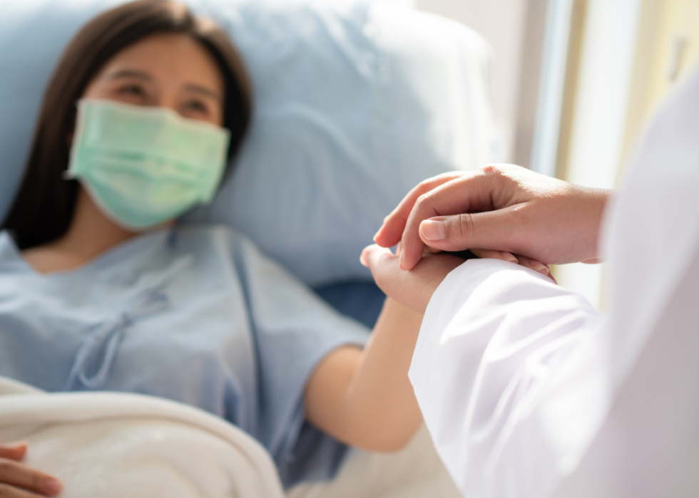 Doctor holding patient's hand and making her smile.