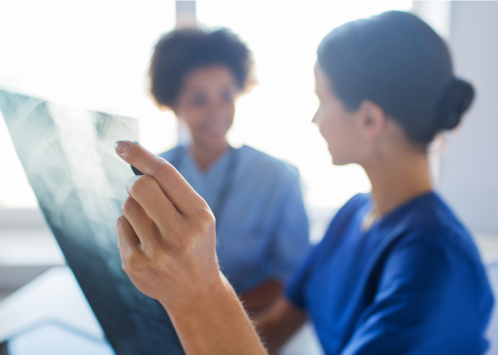 Two female medical professionals look at xrays.