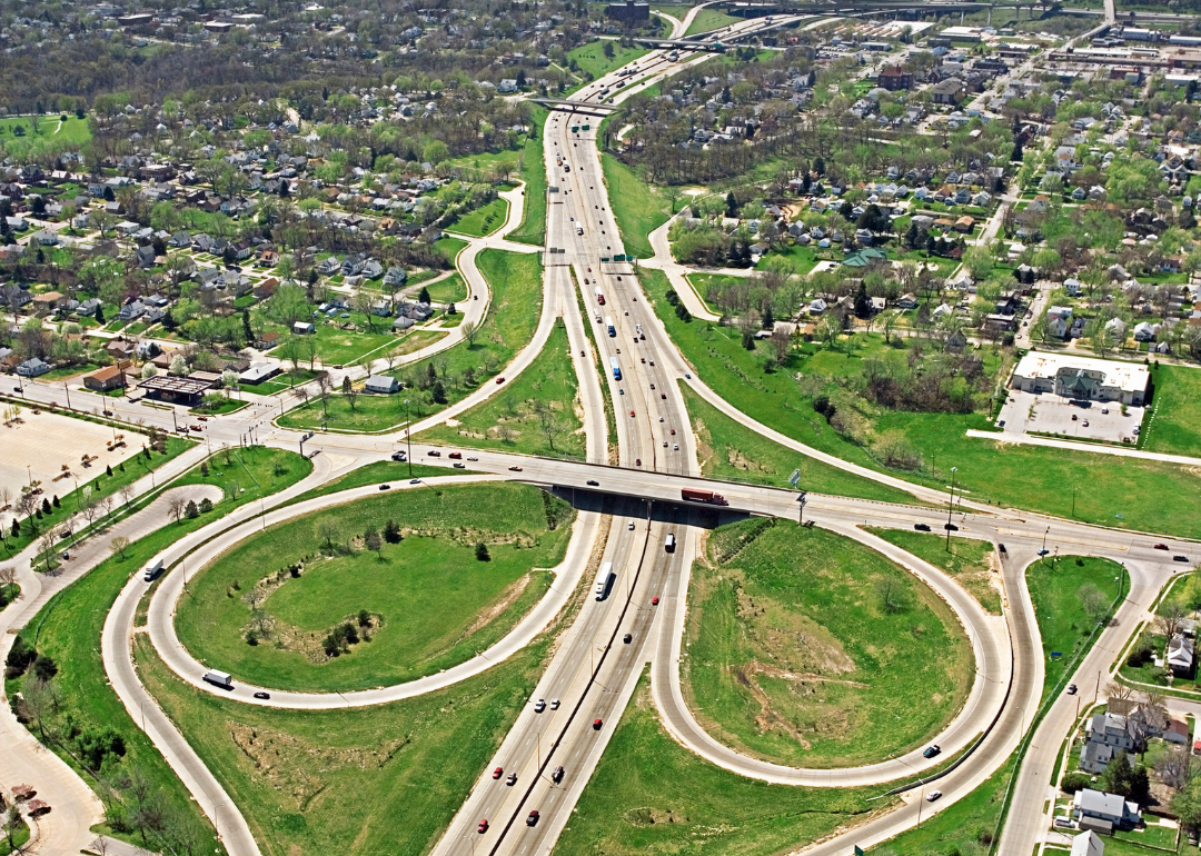 A freeway interchange surrounded by greenery and homes.
