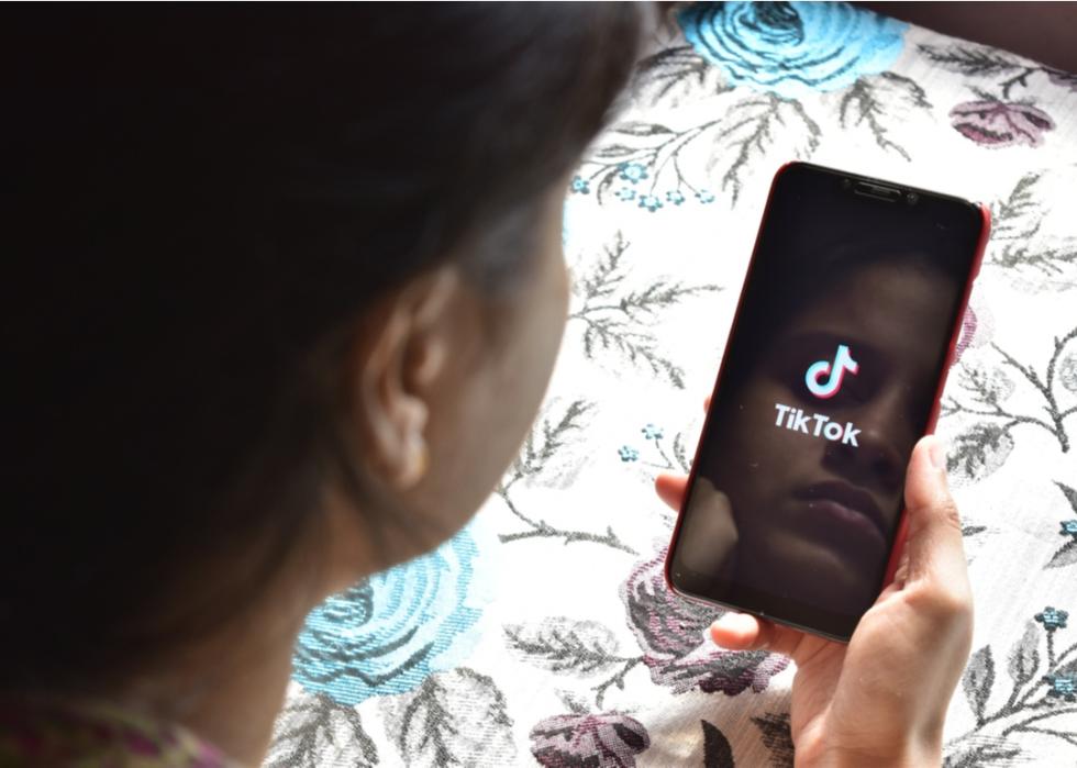 Girl's reflection in her phone as she opens TikTok.