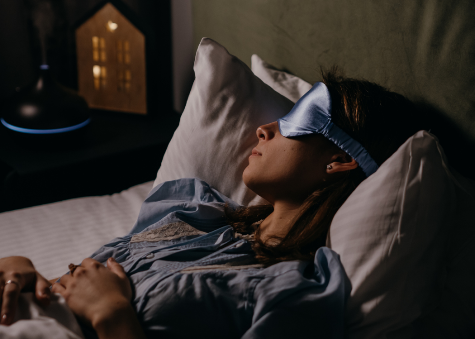 Woman with sleep mask on in dark room.