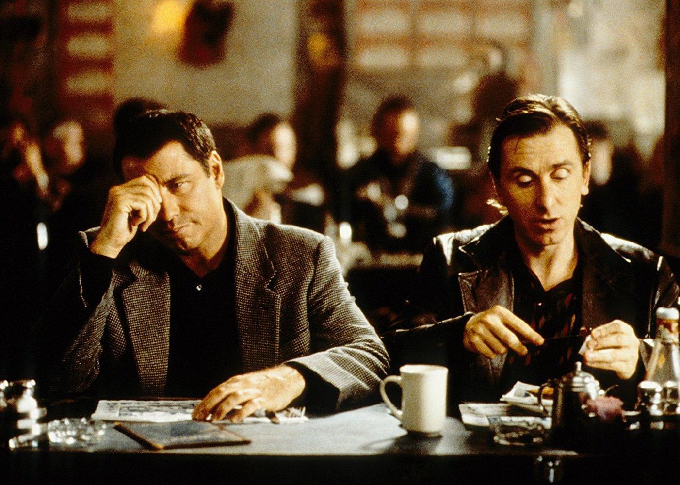 John Travolta and Tim Roth sit at a restaurant having coffee.