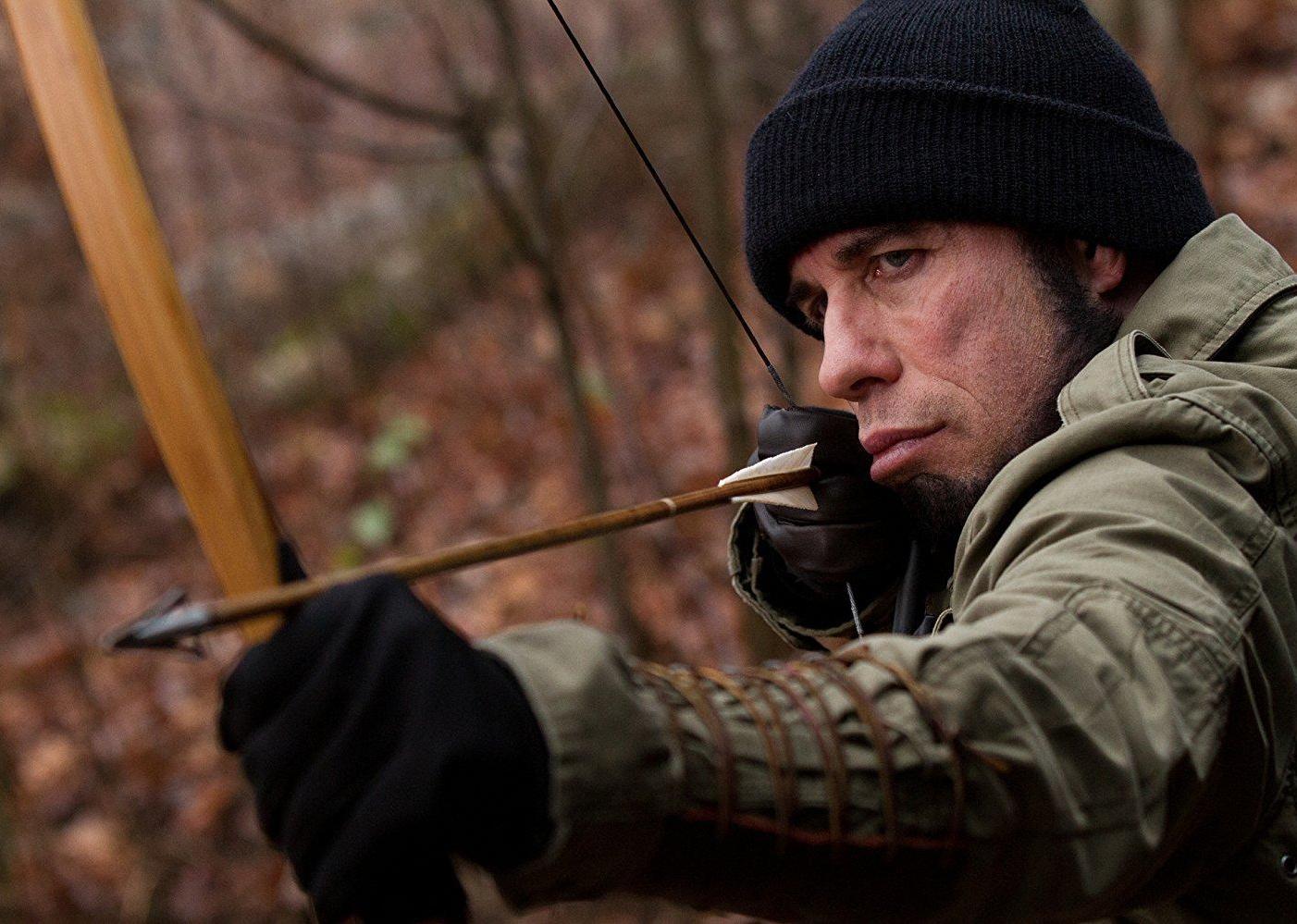 John Travolta shooting a bow and arrow.