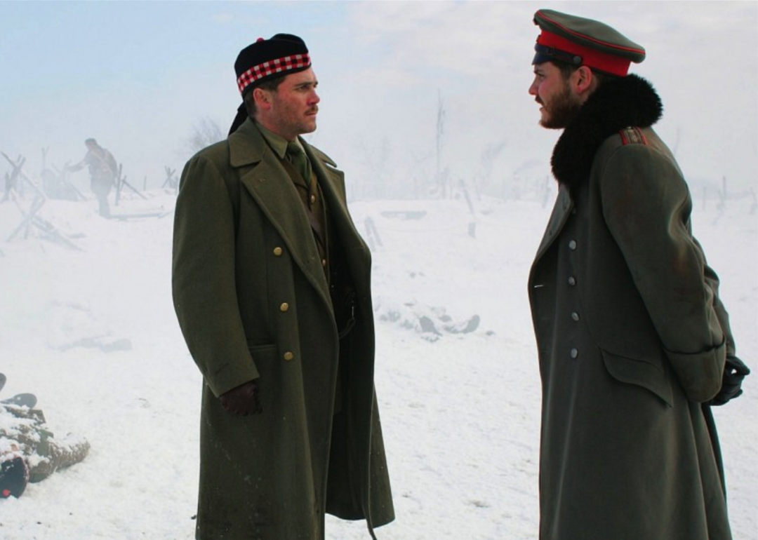 Two men in military uniforms and coats stand in the snow.