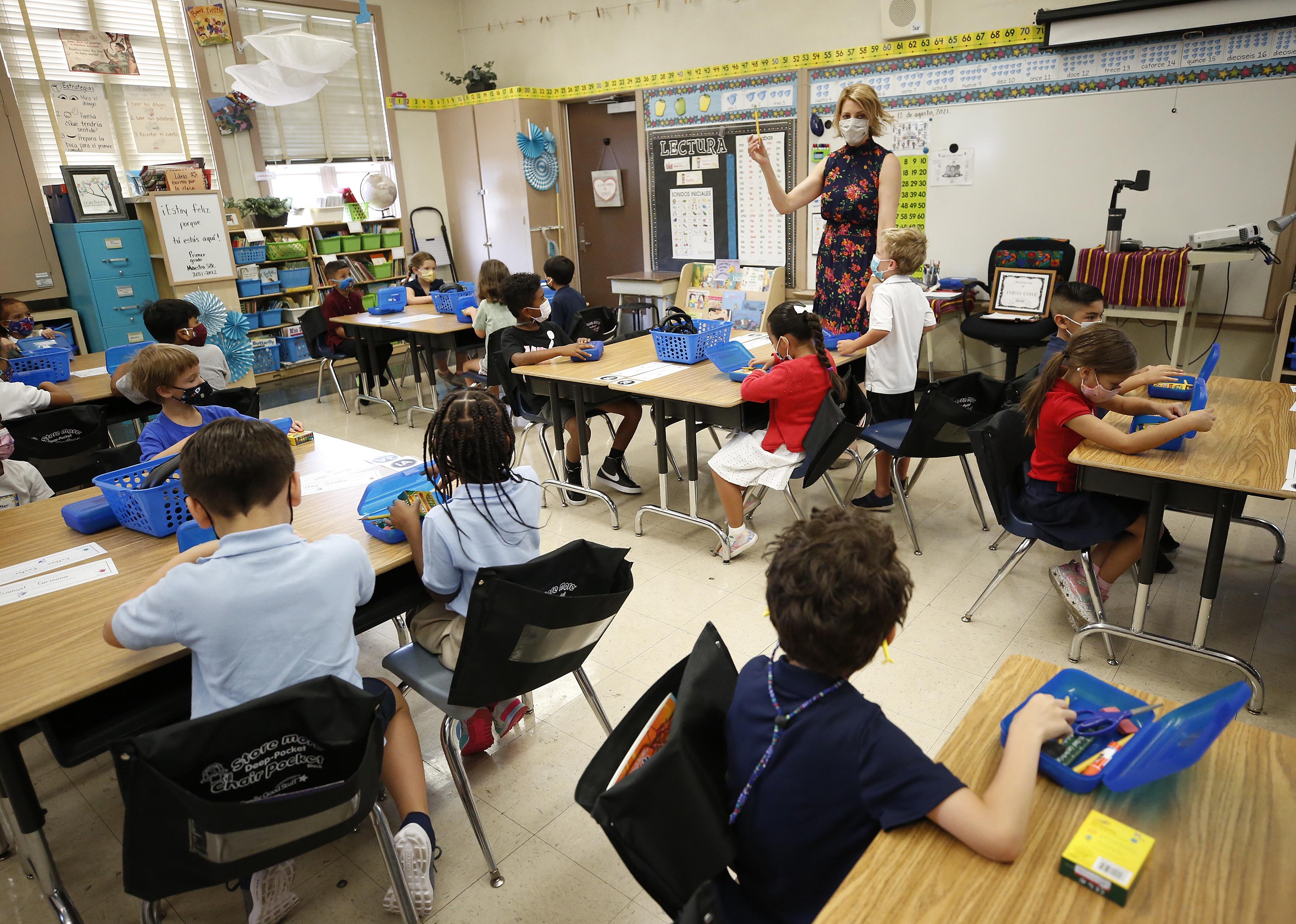 A teacher with the attention of all the students in the classroom on her as she holds up a ruler.