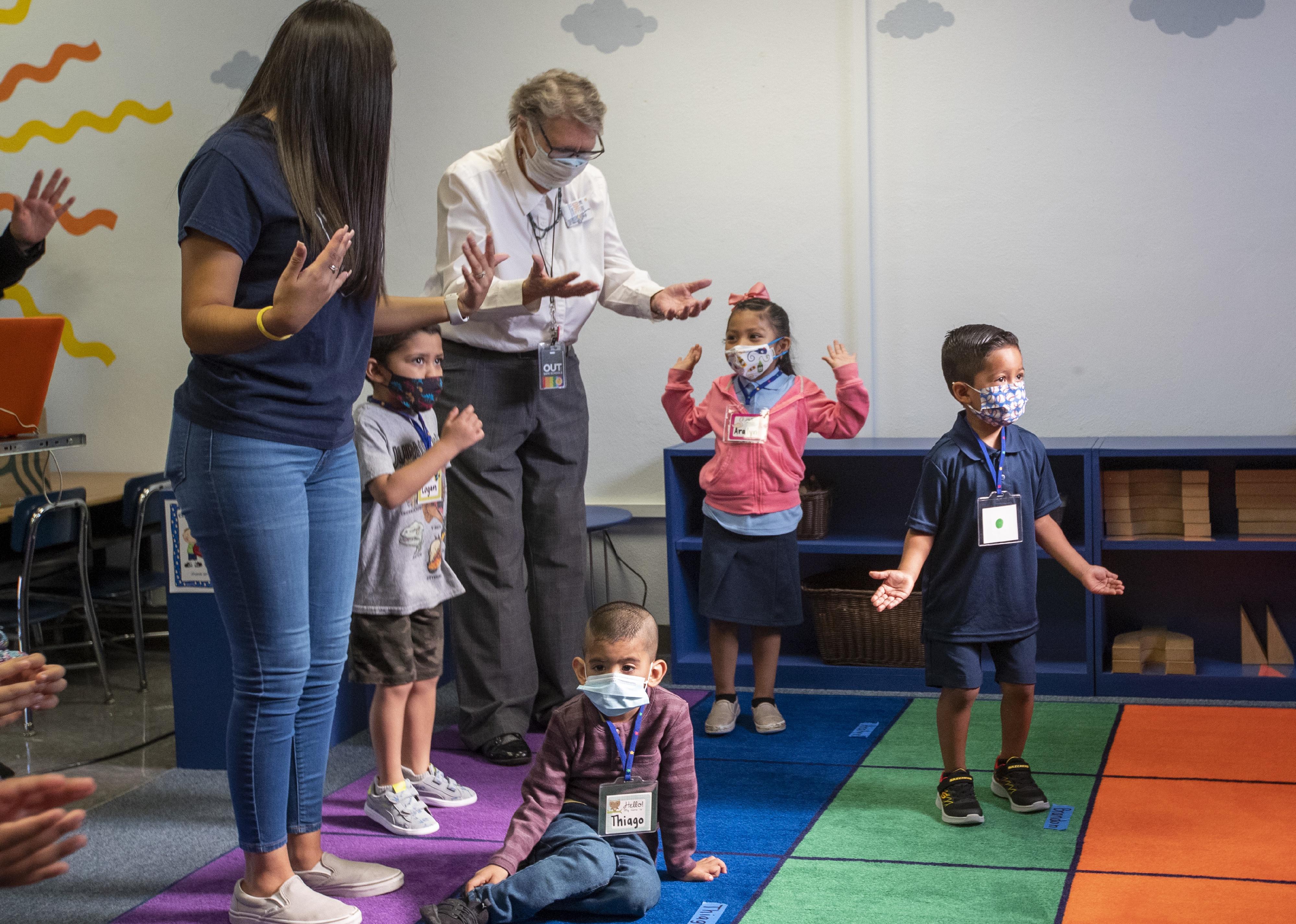 Teachers dance with kindergarten students wearing masks.