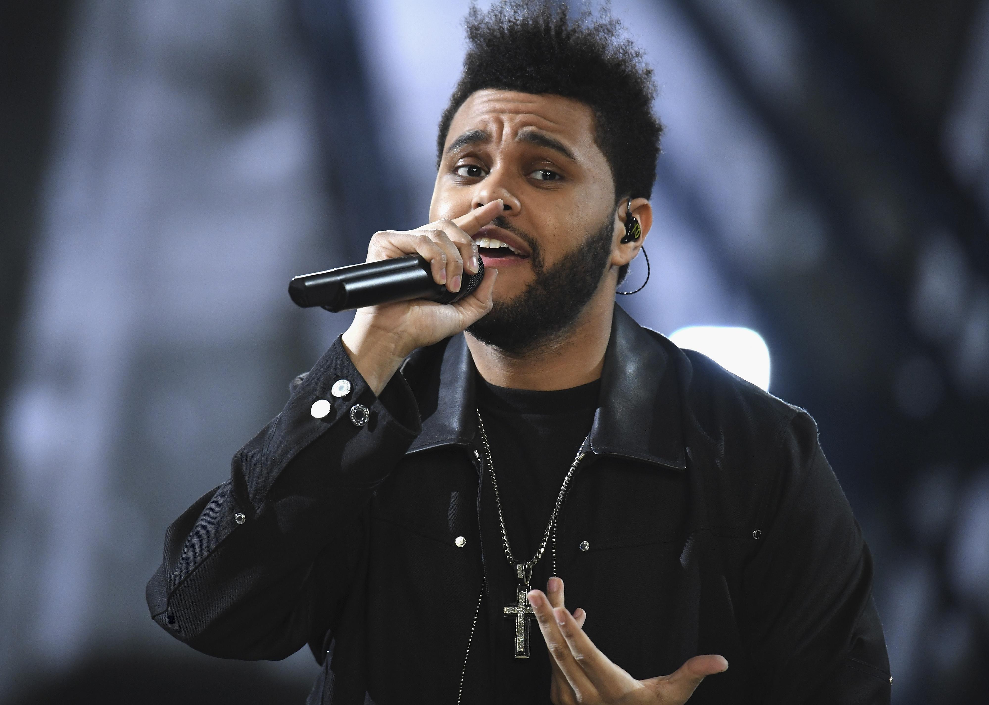 The Weeknd performing onstage in a black leather jacket.