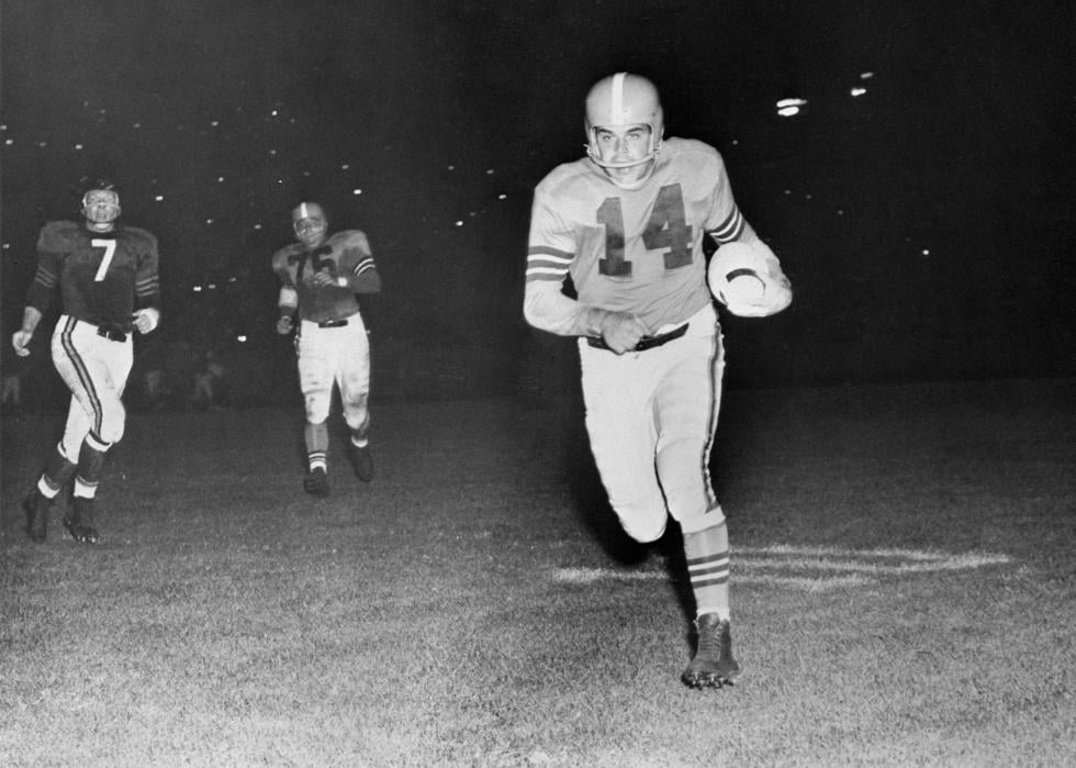 Otto Graham (14) Cleveland Brown quarterback scoring a touchdown as Ed Sprinkle (7) Chicago Bears, tries to catch Graham. September 15, 1955.
