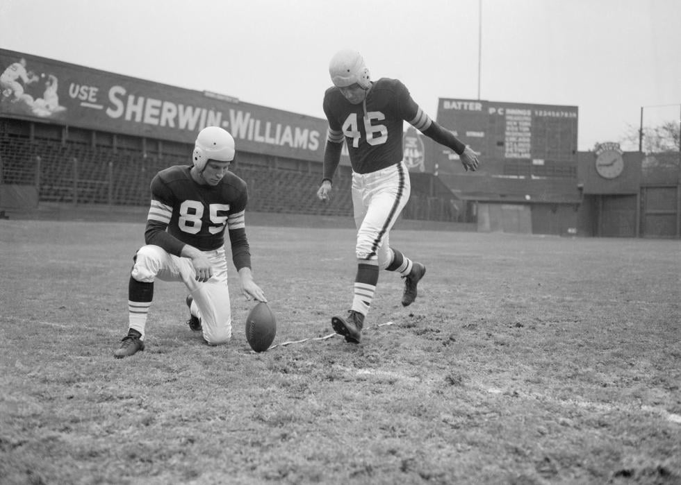 Lou Groza prepares to kick the football for a field goal while his teammate Don Greenwood holds the ball.