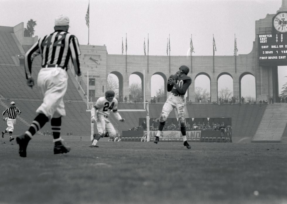 At a Pro Bowl Game at the Memorial Coliseum in LA referees look on as a Jack Butler, #20 East, reception put him at odds with Jack Christiansen, #24 West, sizes him up for a tackle, 1956.