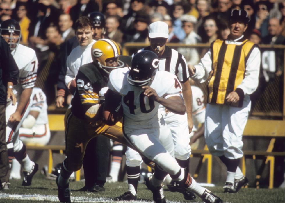Gale Sayers #40 of the Chicago Bears carrying the ball trying to avoid the tackle of Willie Wood #24 of the Green Bay Packers in a late circa 1960's NFL football game at Lambeau Field in Green Bay, Wisconsin. 