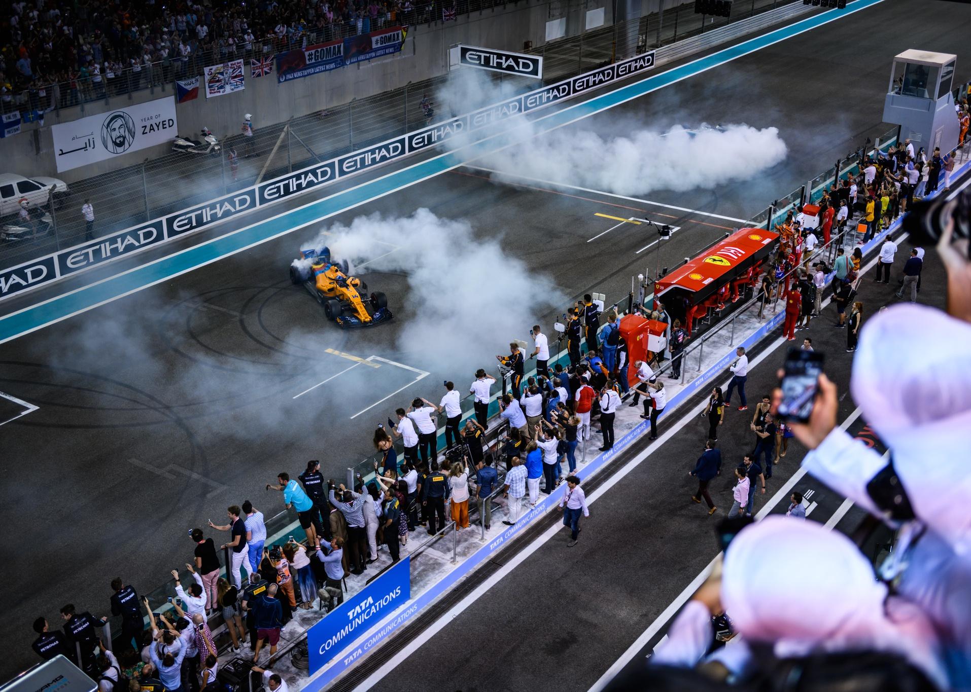 A racecar with smoke trailing above as fans watch.
