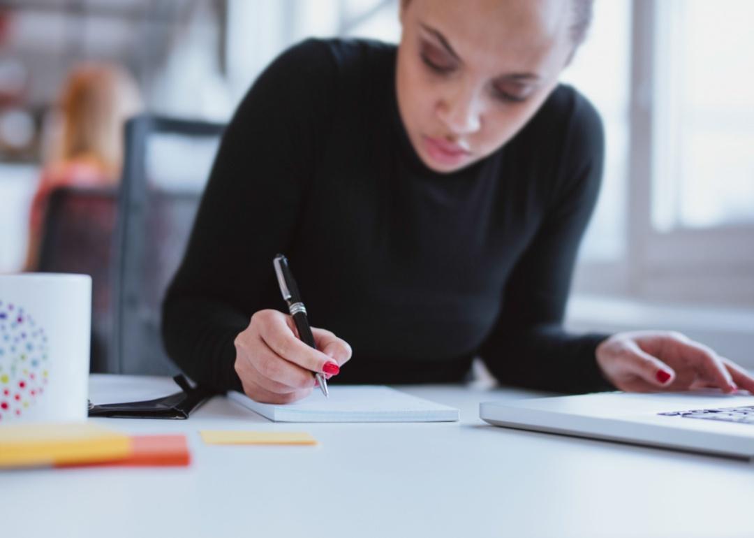 A woman in a black shirt concentrating while taking notes.