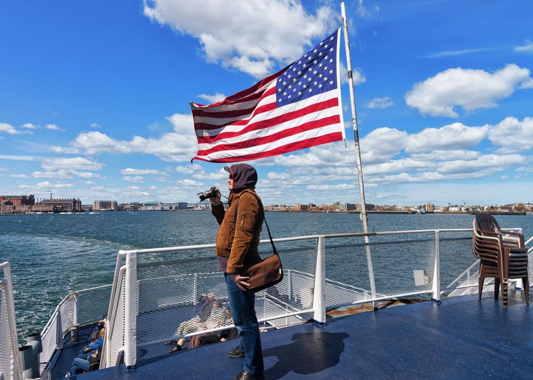 A person holding a camera on a boat with an American flag in the background.