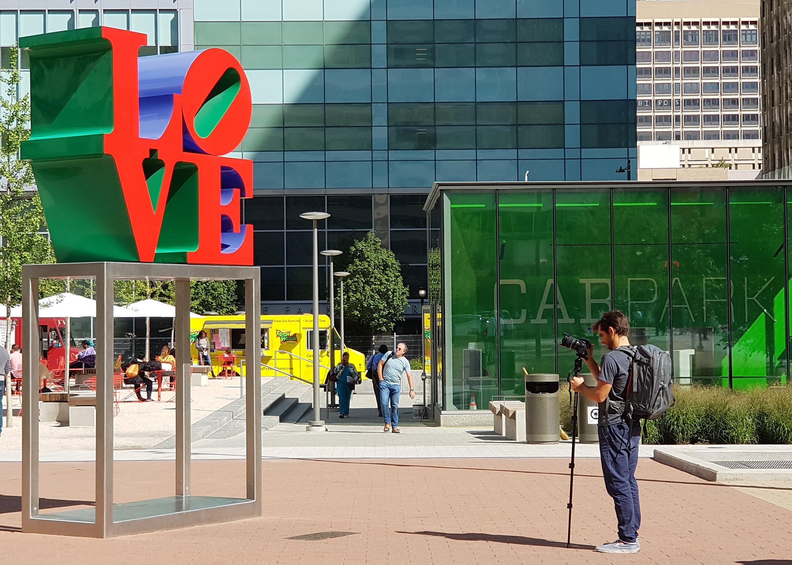 A person taking a photo of a "Love" sign in Philadelphia.