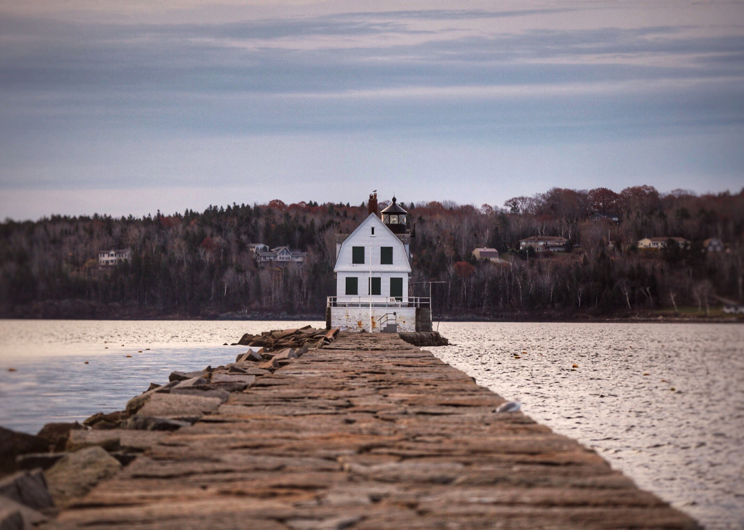 A lighthouse in Rockland with homes across the water.